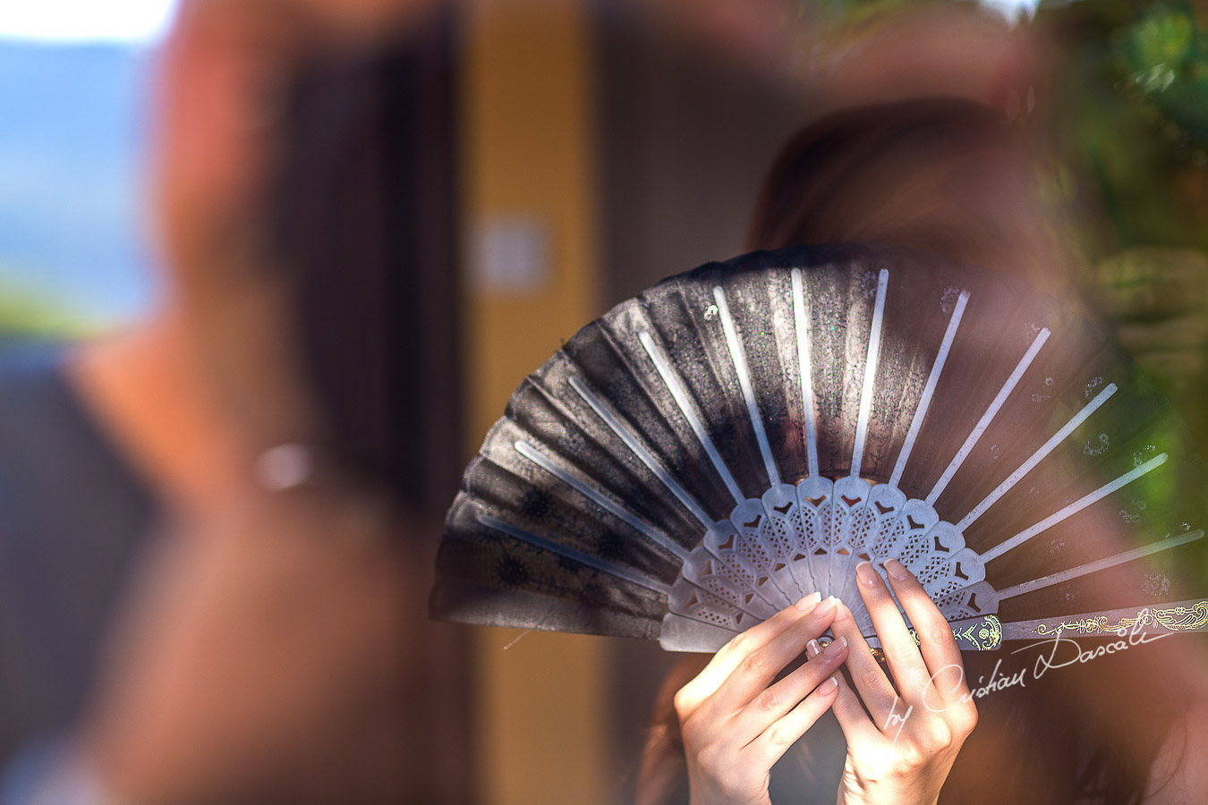 Rindala, the bride hiding from the photographer using a traditional fan.