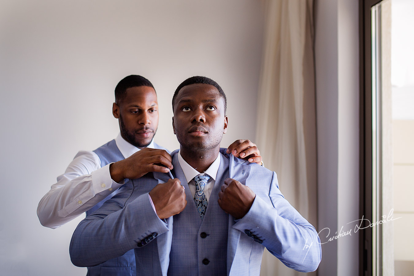 Moments when best man is helping the groom to dress captured at a a wedding at Minthis Hills in Cyprus, by Cristian Dascalu.