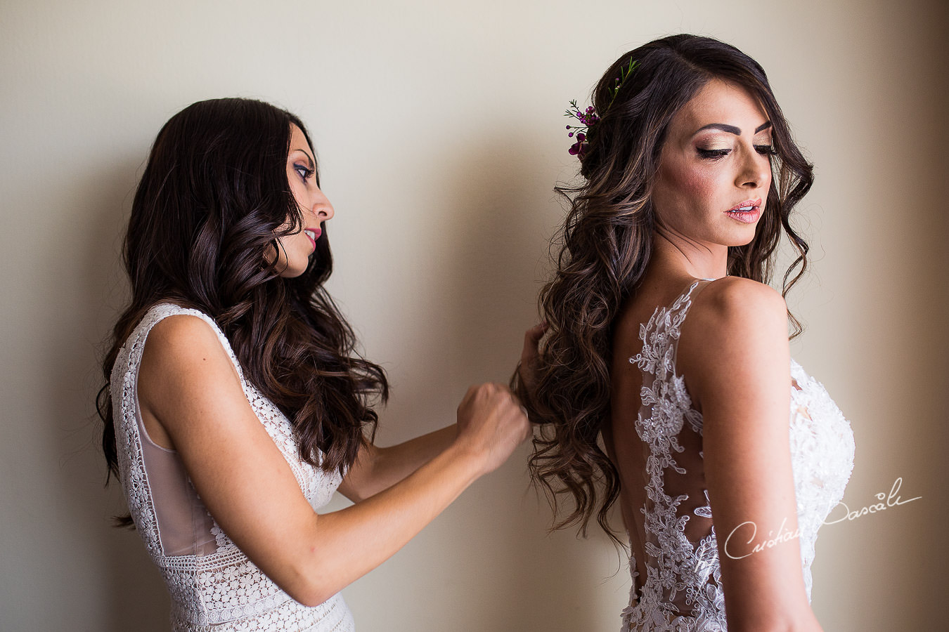 Christiana, the bride, helped by her koumera while getting ready for her wedding ceremony, moments captured at a wedding in Cyprus by Cristian Dascalu Photographer.