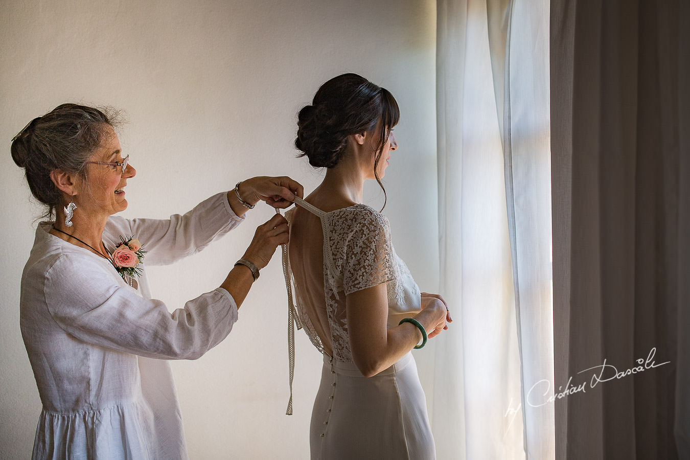 A beautiful wedding day at the Vasilias Nikoklis Inn in Paphos, captured by Cristian Dascalu. Sarah's mother is getting her ready for the wedding ceremony.