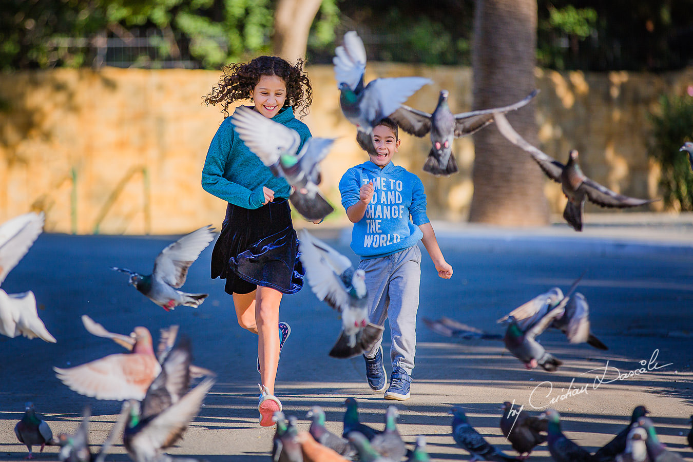 Young brother and sister running through the pigeons, moments captured by Cristian Dascalu during a beautiful Limassol family photography photo session.