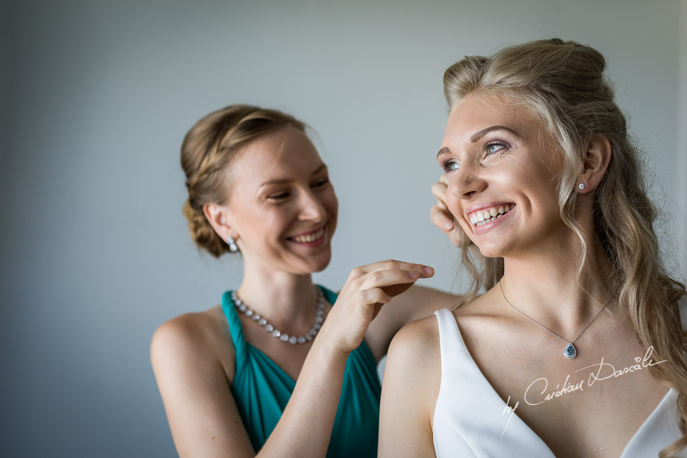Maid of Honor helping the bride to get ready, moments captured during an Exquisite Wedding at Asterias Beach Hotel. Photography by Cyprus Photographer Cristian Dascalu.