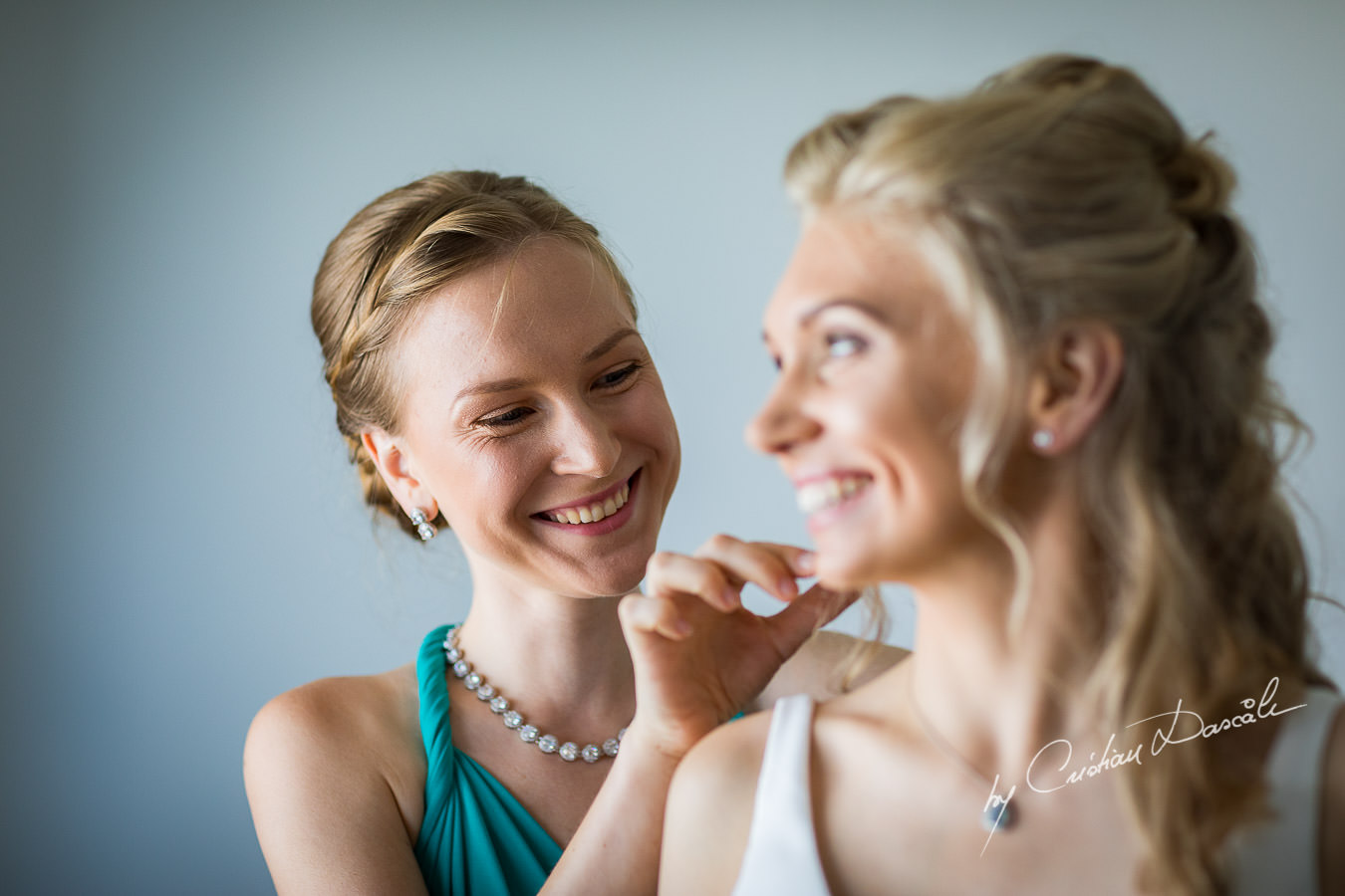 Maid of Honor helping the bride to get ready, moments captured during an Exquisite Wedding at Asterias Beach Hotel. Photography by Cyprus Photographer Cristian Dascalu.