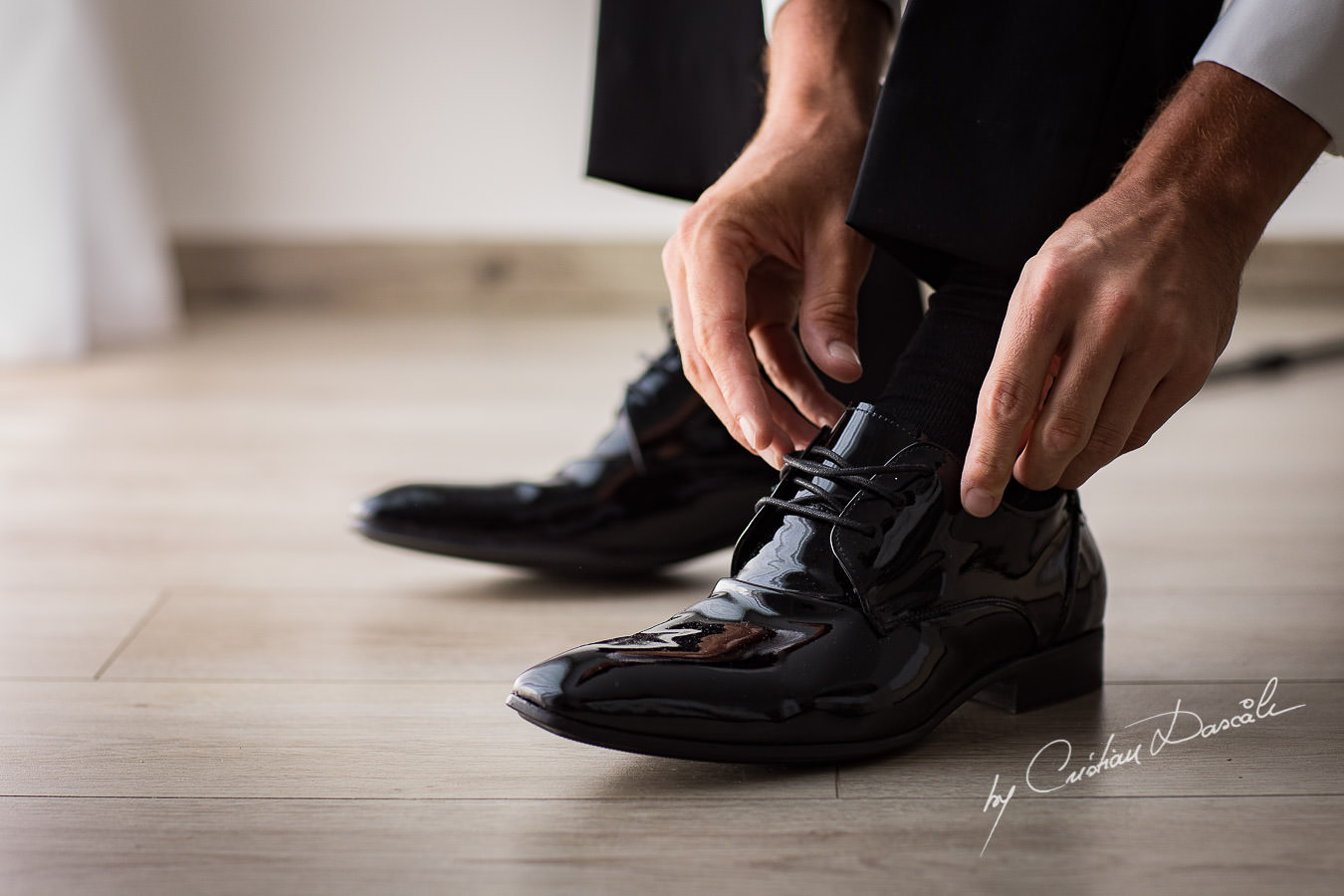 The groom is tying his shoe laces, moments captured by Cristian Dascalu during an elegant Aphrodite Hills Wedding in Cyprus.