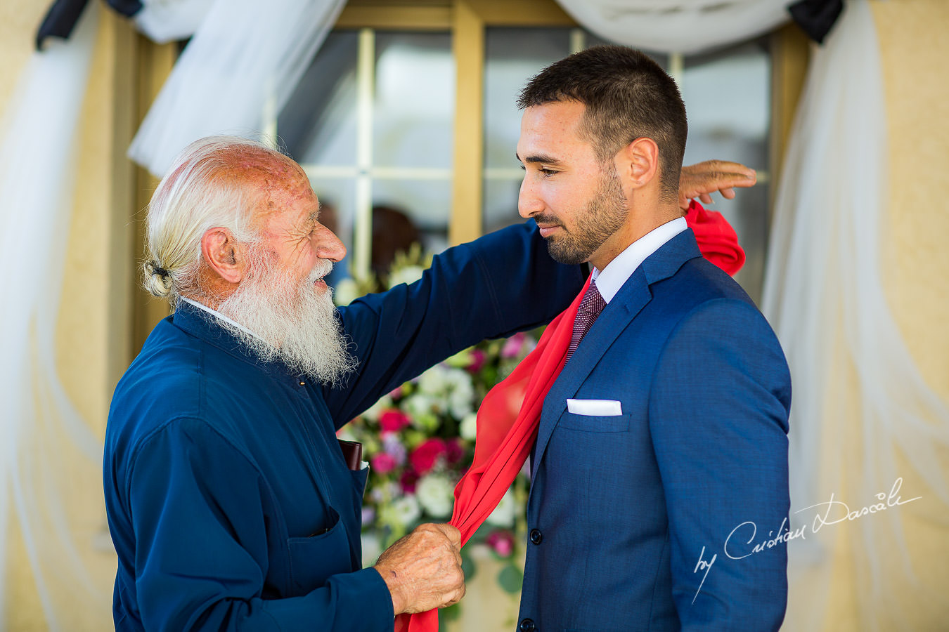 The grandfather of the groom, also the priest`s village is blessing him with the red scarf, moments captured by Cyprus Wedding Photographer Cristian Dascalu at a beautiful wedding in Larnaka, Cyprus.